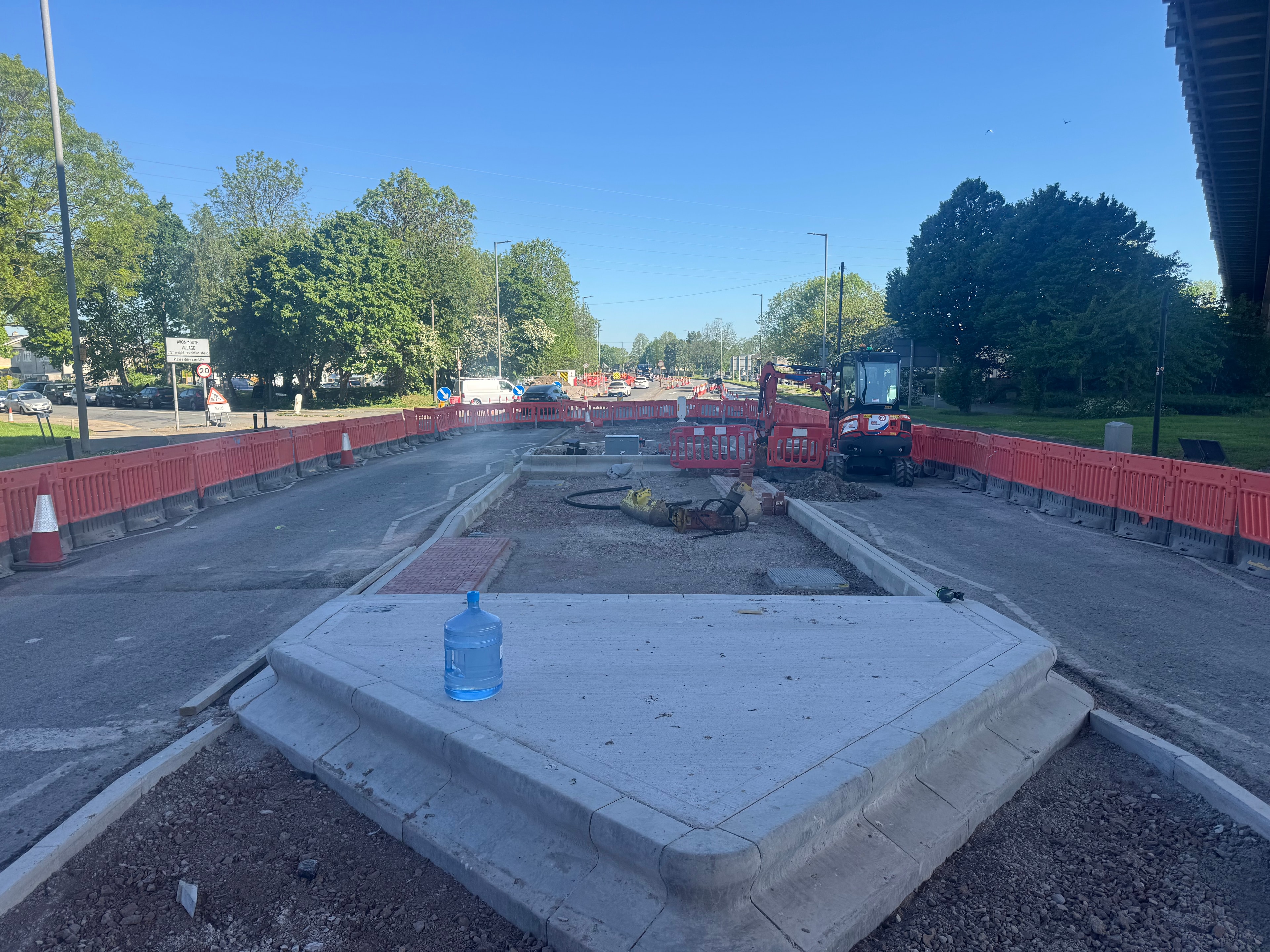 Road construction works with red barriers and excavator